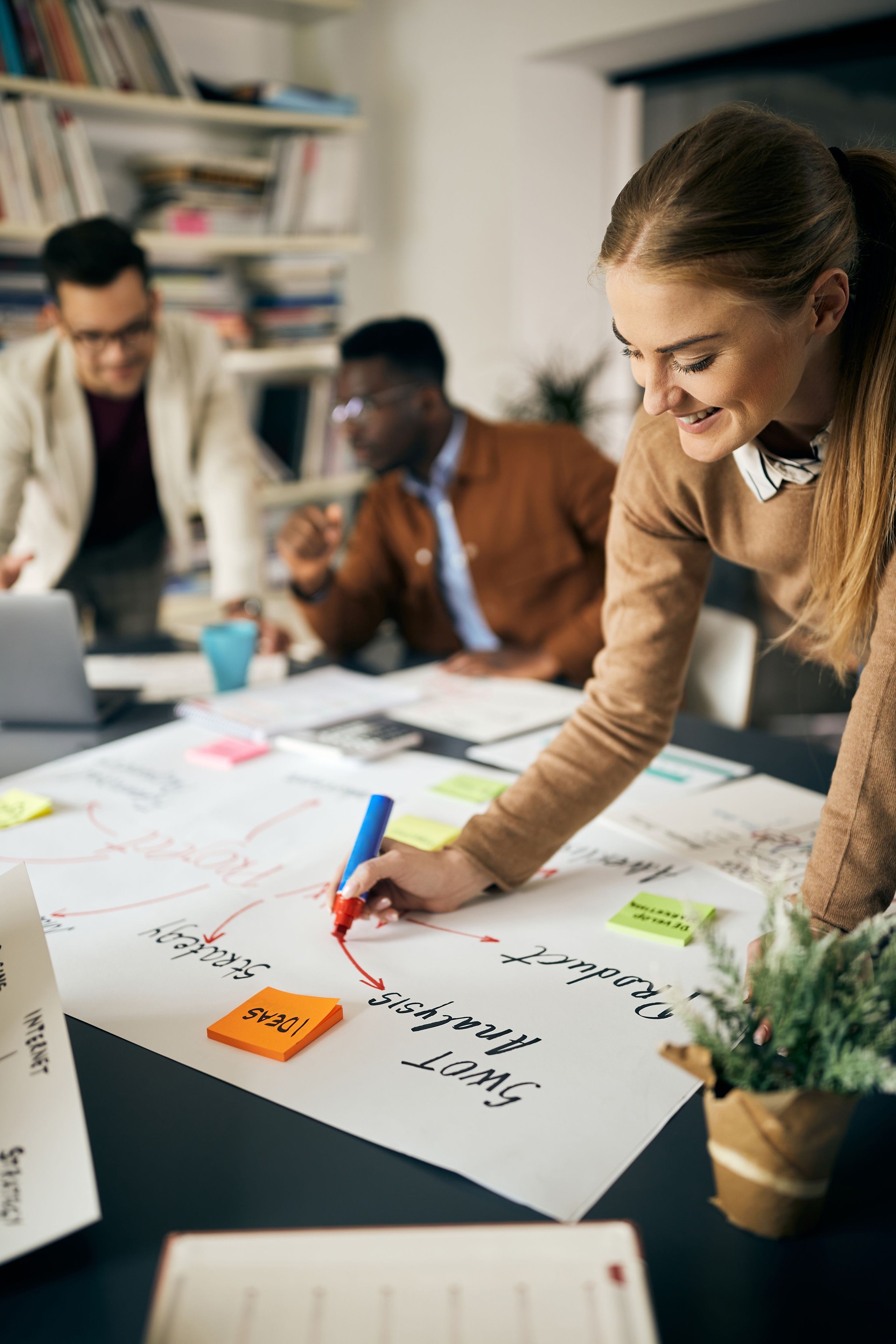 Happy creative woman drawing business plan on paperboard during a meeting in the office.
